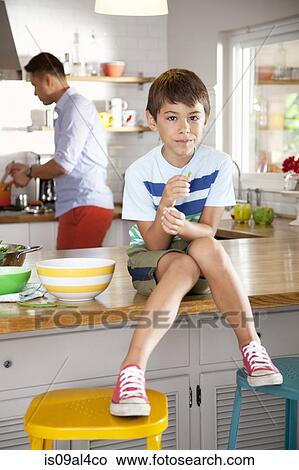 Picture - Boy sitting on kitchen counter. Fotosearch