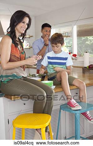 Stock Photography - Boy sitting on kitchen counter with mother and father. Fotosearch