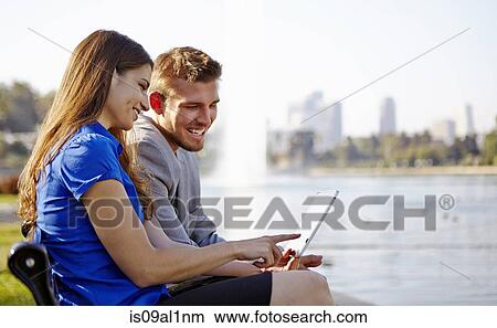 Businessman and woman using laptop by lake, Echo Park, Los Angeles, California, US View Large Photo Image Picture - Businessman and woman using laptop by lake, Echo Park, Los Angeles, California, US. Fotosearch
