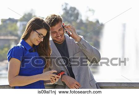 Stock Image - Businessman and woman using smartphone. Fotosearch