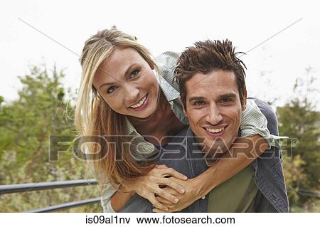 Couple playing piggyback ride in park View Large Photo Image Stock Photo - Couple playing piggyback ride in park. Fotosearch
