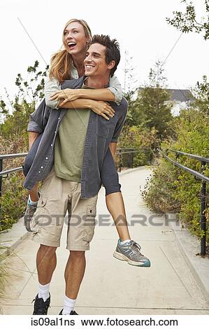 Couple playing piggyback ride in park View Large Photo Image Stock Photograph - Couple playing piggyback ride in park. Fotosearch