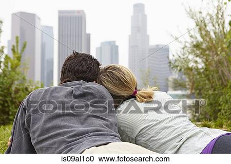 Stock Image - Couple relaxing in park by city. Fotosearch