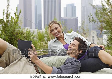 Couple relaxing in park by city View Large Photo Image Stock Photo - Couple relaxing in park by city. Fotosearch