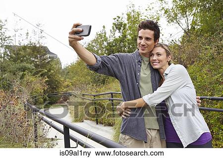 Stock Photo - Couple taking selfie in park. Fotosearch
