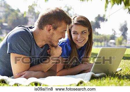 Couple using laptop in park View Large Photo Image Stock Photo - Couple using laptop in park. Fotosearch