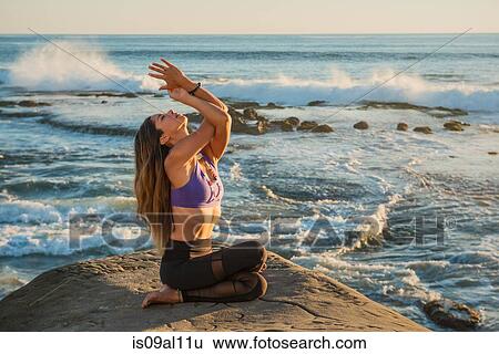 Stock Photograph - Cow face pose with eagle arms, Windansea beach, La Jolla, California. Fotosearch