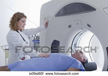 Stock Image - Doctor preparing patient for CT scanning. Fotosearch