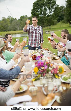 Stock Photograph - Family and friends making a toast at outdoor meal. Fotosearch