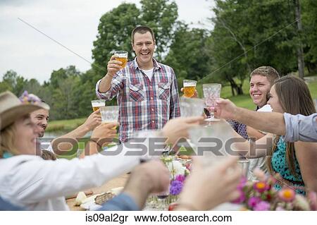 Stock Photography - Family and friends making a toast at outdoor meal. Fotosearch