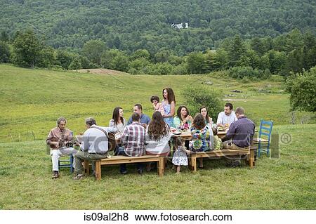 Family having meal together and socialising, outdoors View Large Photo Image Stock Photo - Family having meal together and socialising, outdoors. Fotosearch