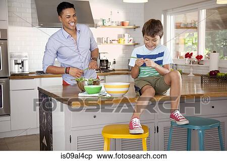 Stock Photography - Father and son in kitchen, boy sitting on counter. Fotosearch
