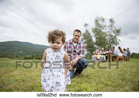Stock Image - Father playing with daughter at family gathering, outdoors. Fotosearch
