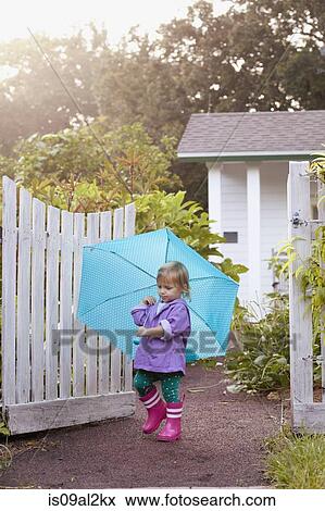 Female toddler walking in garden carrying umbrella View Large Photo Image Stock Photo - Female toddler walking in garden carrying umbrella. Fotosearch