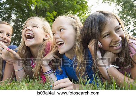 Stock Image - Friends lying on grass. Fotosearch