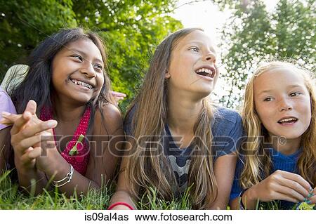 Stock Photograph - Friends lying on grass. Fotosearch