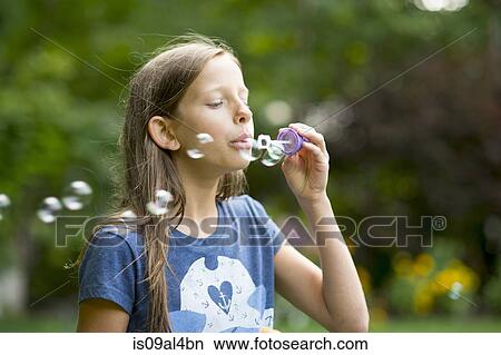 Girl blowing bubbles in garden View Large Photo Image Picture - Girl blowing bubbles in garden. Fotosearch