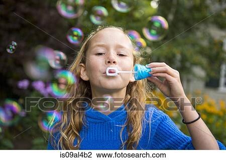 Stock Image - Girl blowing bubbles in garden. Fotosearch