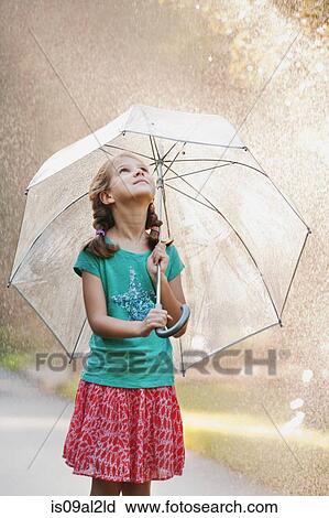 Stock Image - Girl holding up umbrella on rainy street. Fotosearch