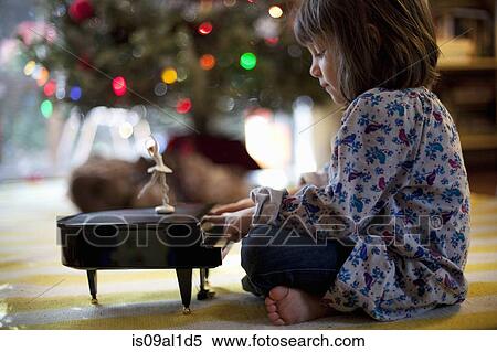 Girl sitting on living room floor playing toy piano music box at Xmas View Large Photo Image Stock Photography - Girl sitting on living room floor playing toy piano music box at Xmas. Fotosearch