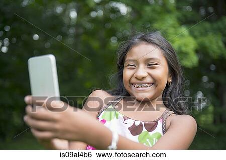 Stock Photograph - Girl taking selfie in garden. Fotosearch