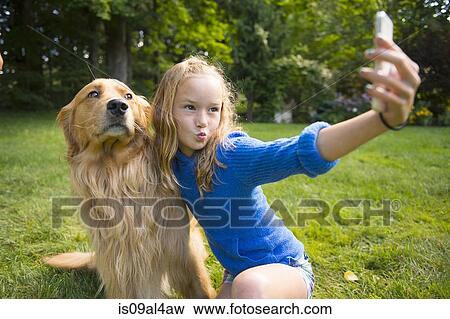 Stock Photo - Girl taking selfie with pet dog in garden. Fotosearch