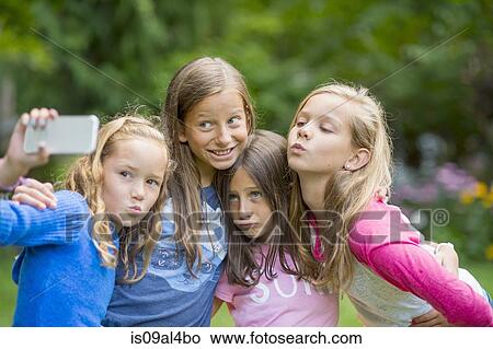 Picture - Girls taking selfie in garden. Fotosearch