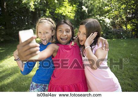Stock Photo - Girls taking selfie in garden. Fotosearch