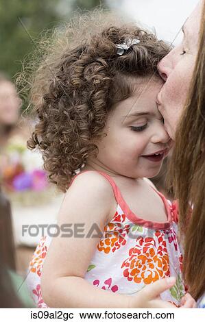 Stock Image - Grandmother kissing granddaughter on forehead. Fotosearch
