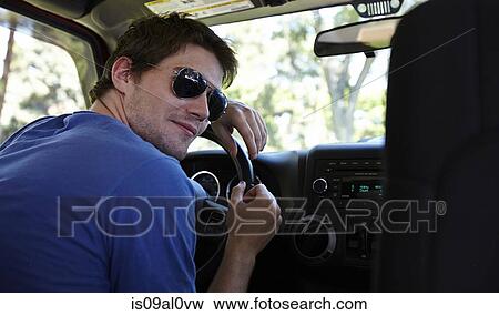 Stock Photo - Man looking over shoulder inside car. Fotosearch