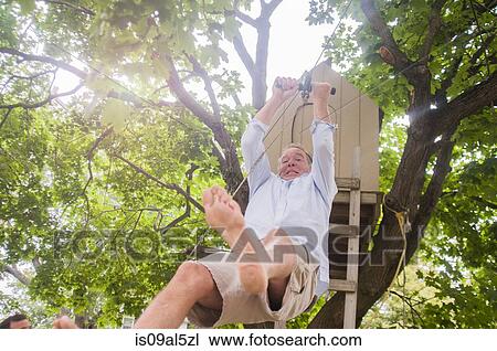 Mature man sliding down on pulley from tree house View Large Photo Image Stock Image - Mature man sliding down on pulley from tree house. Fotosearch