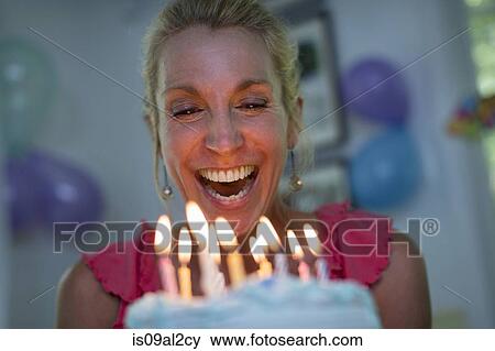 Stock Photo - Mature woman holding birthday cake with candles. Fotosearch