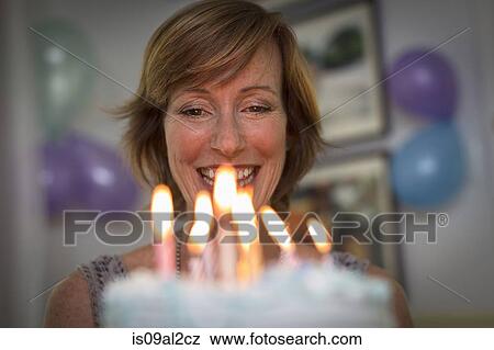 Stock Photo - Mature woman holding birthday cake with candles. Fotosearch