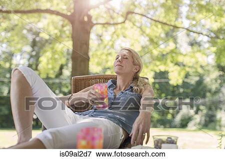 Mature woman relaxing in garden with drink View Large Photo Image Stock Photo - Mature woman relaxing in garden with drink. Fotosearch