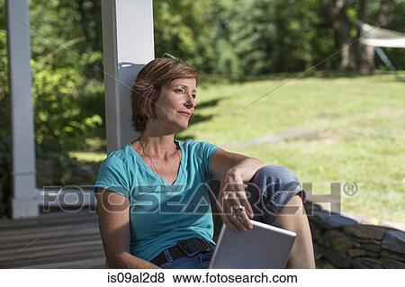 Stock Photo - Mature woman relaxing on veranda. Fotosearch