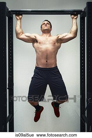 Mid adult male doing pull ups on exercise bar in gym View Large Photo Image Stock Image - Mid adult male doing pull ups on exercise bar in gym. Fotosearch