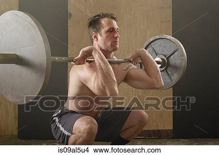 Mid adult male weightlifter lifting barbell in gym View Large Photo Image Picture - Mid adult male weightlifter lifting barbell in gym. Fotosearch