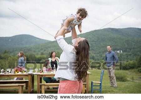 Mid adult woman holding baby girl in air at family gathering, outdoors View Large Photo Image Stock Image - Mid adult woman holding baby girl in air at family gathering, outdoors. Fotosearch