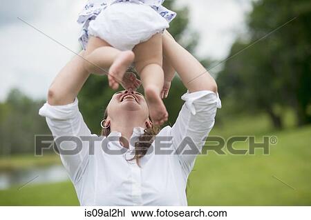 Mid adult woman holding baby girl in air, outdoors View Large Photo Image Stock Image - Mid adult woman holding baby girl in air, outdoors. Fotosearch