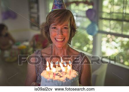 Portrait of mature woman holding birthday cake with candles View Large Photo Image Stock Photo - Portrait of mature woman holding birthday cake with candles. Fotosearch