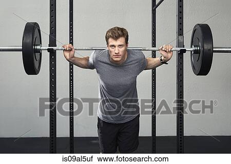 Portrait of mid adult male weightlifter lifting barbell in gym View Large Photo Image Stock Image - Portrait of mid adult male weightlifter lifting barbell in gym. Fotosearch