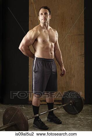 Stock Image - Portrait of muscular mid adult male weightlifter with barbell in gym. Fotosearch