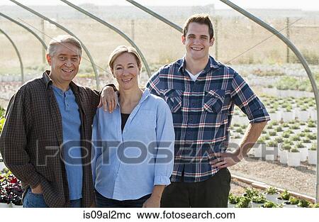 Stock Image - Portrait of three workers in plant nursery polytunnel. Fotosearch