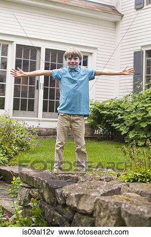 Stock Photo - Portrait of young boy in garden, arms outstretched. Fotosearch