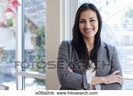 Stock Image - Portrait of young businesswoman woman standing next to window. Fotosearch