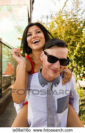 Portrait of young man giving girlfriend a piggy back View Large Photo Image Picture - Portrait of young man giving girlfriend a piggy back. Fotosearch