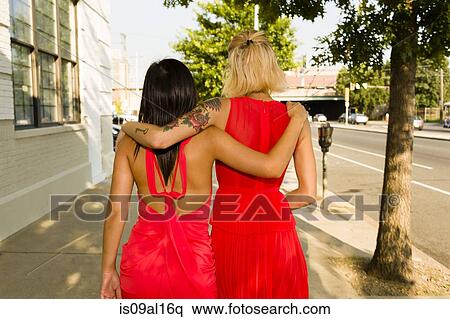 Rear view of two young women wearing red dresses strolling on street View Large Photo Image Stock Photography - Rear view of two young women wearing red dresses strolling on street. Fotosearch