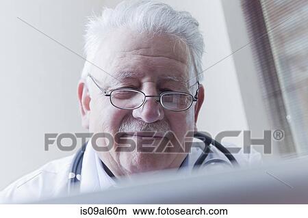 Picture - Senior doctor reading digital tablet. Fotosearch