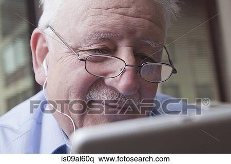 Stock Photography - Senior man reading digital tablet. Fotosearch