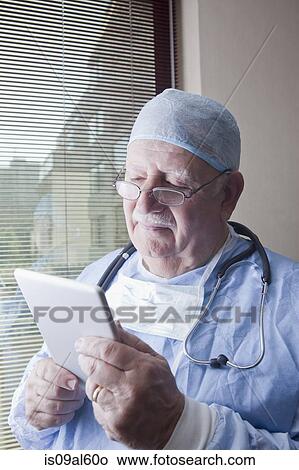 Senior surgeon reading digital tablet View Large Photo Image Picture - Senior surgeon reading digital tablet. Fotosearch